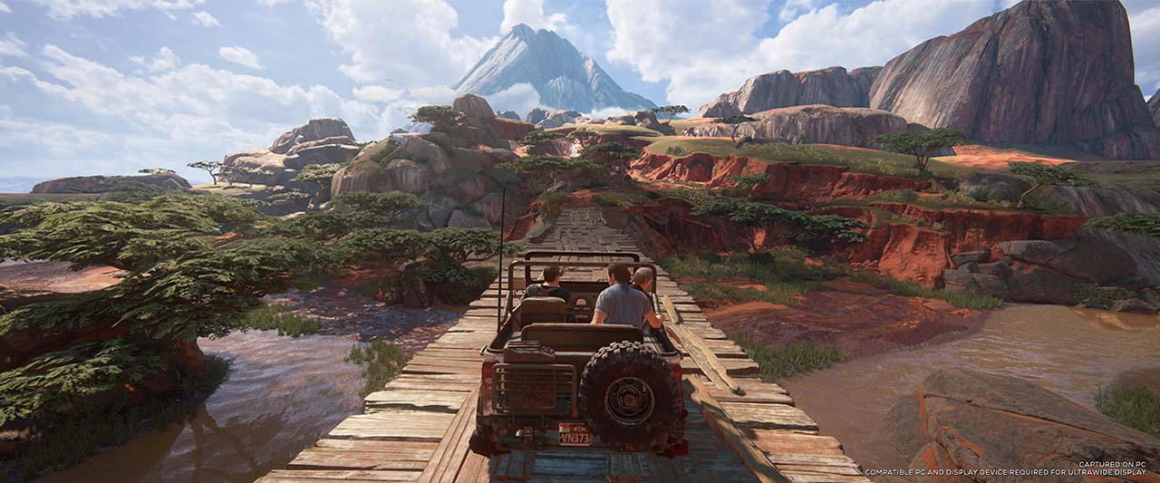 A jeep roars over a wooden bridge in the foreground, surrounded by a lush vista, which stretches off into the distance. Compatible PC and display device required for ultrawide display.